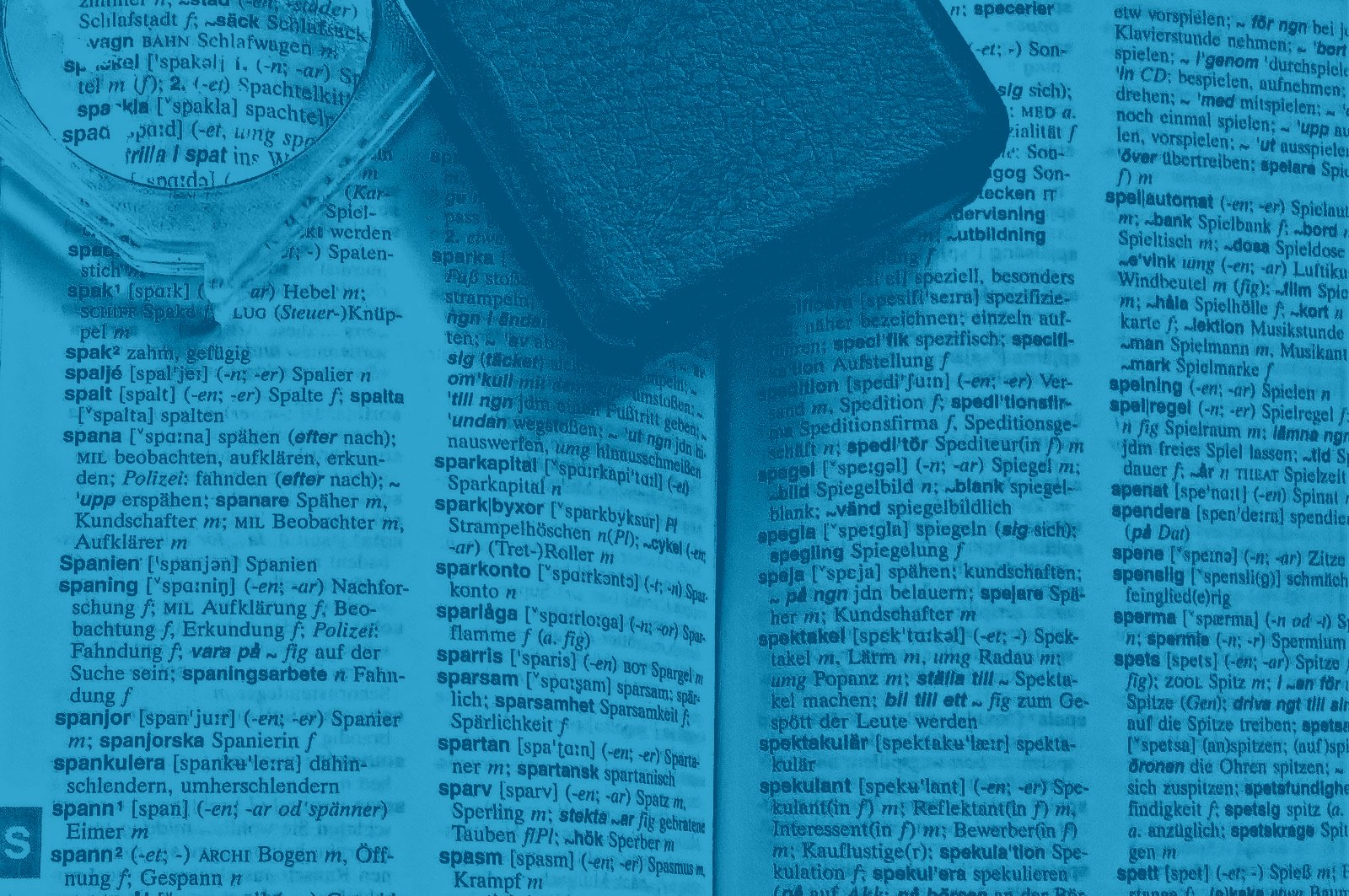 A bilingual dictionary open under a magnifying glass and a phone, in blue